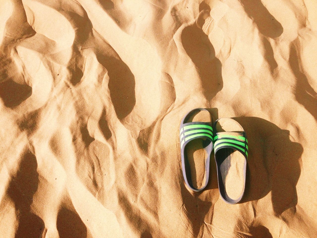 high angle view, sand, shadow, shoe, sunlight, low section, leisure activity, lifestyles, pattern, beach, day, outdoors, standing, footwear, street, person, textured, men