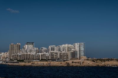 Building by sea against clear blue sky