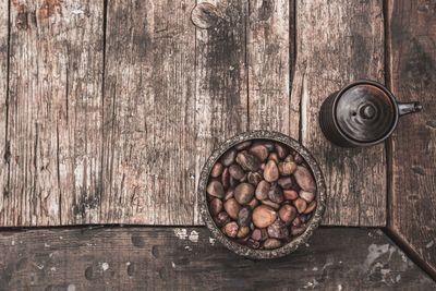 Directly above shot of kettle with pebbles in bowl on wooden table