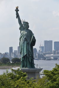 Statue in city against sky