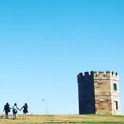 Rear view of women walking at la perouse against clear sky