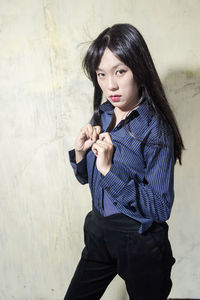 Beautiful young woman standing against wall