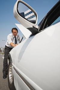 Man standing by car against sky