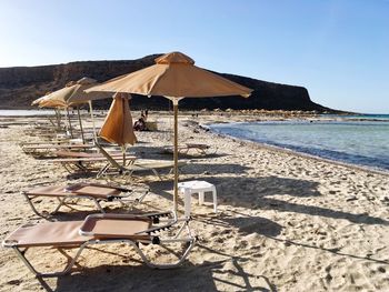 Deck chairs on beach against clear sky