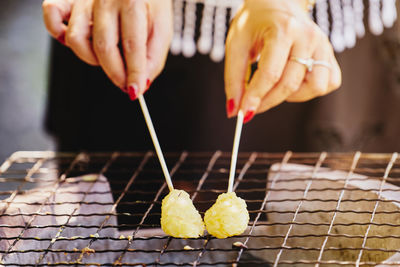 Close-up of person preparing food on barbecue grill