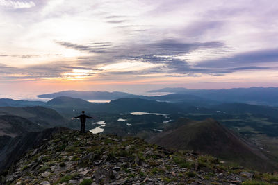 Man standing on mountain against sky during sunset