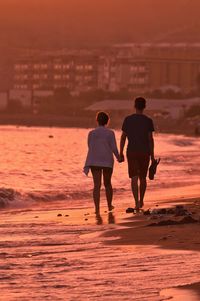 Rear view of people on beach during sunset