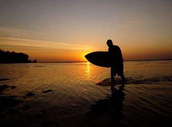 Silhouette of people on beach at sunset