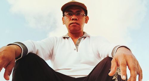 Low angle view of man sitting against sky