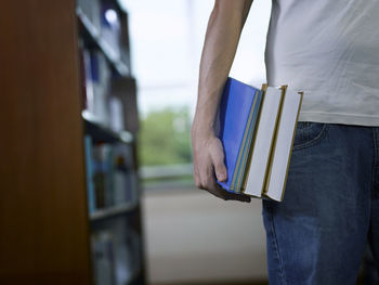 Midsection of man holding books in library