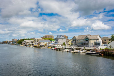 Houses by river against sky in city