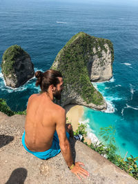 High angle view of shirtless man looking at sea