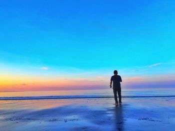 Silhouette of man standing on beach at sunset