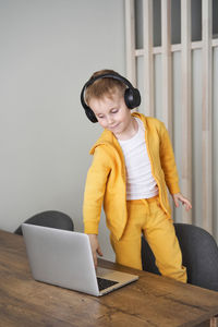 Young woman using phone while sitting on table