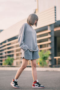 Full length of girl with umbrella on street in city