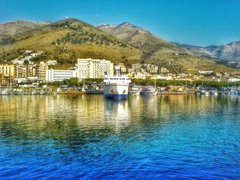 Boats in calm sea with buildings in background