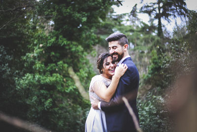 Young couple standing against trees