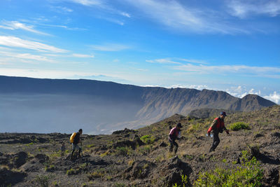 People walking on mountain road against sky. tambora mountain