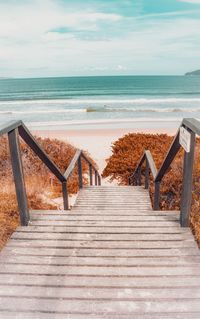 Staircase leading towards sea against sky