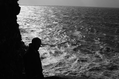 Silhouette woman on sea shore against sky