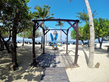 Man riding bicycle by trees against blue sky