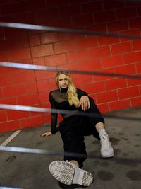 Portrait of woman standing against brick wall