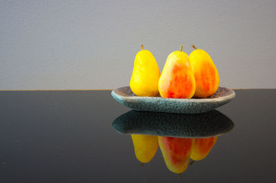Close-up of orange fruits on table against wall