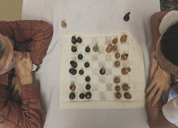 High angle view of grandfather and grandson playing chess on table