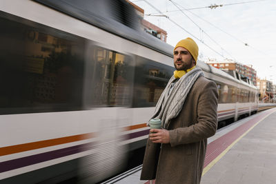 Man standing on train at railroad station