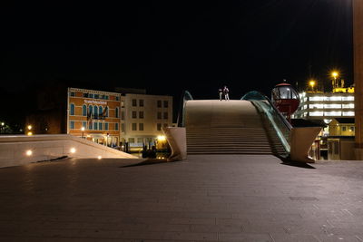 Illuminated street amidst buildings in city at night