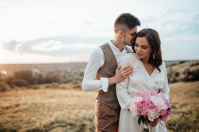 Young couple standing on land against sky