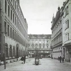 People walking on street in city against sky