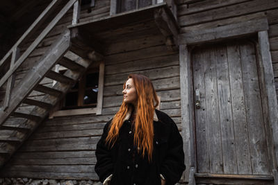 Woman looking away while standing on wood