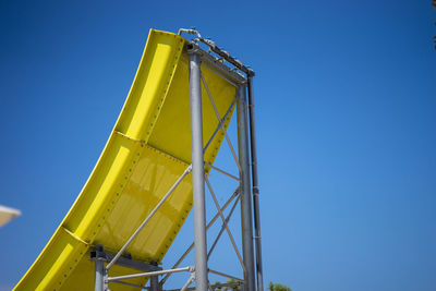 Low angle view of waterslide against clear blue sky