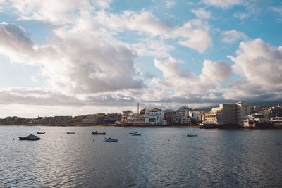 Buildings by sea against sky