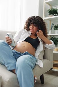 Young woman sitting on sofa at home