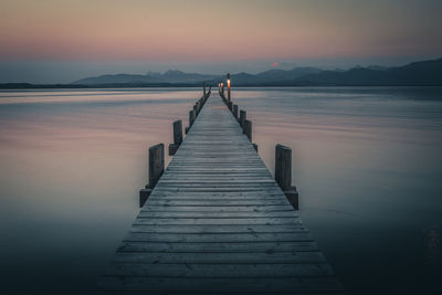 Pier over lake against sky during sunset