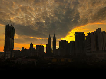 Buildings in city against cloudy sky during sunset