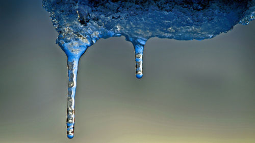 Close-up of icicles against blue sky