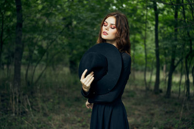 Young woman standing against trees