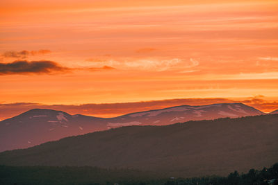 Scenic view of silhouette mountains against orange sky