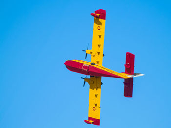 Low angle view of airplane against clear blue sky