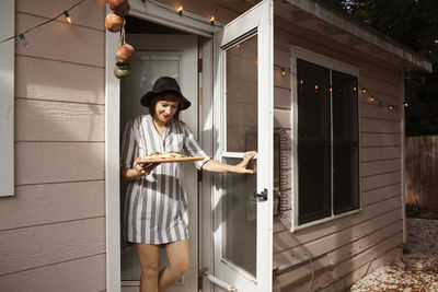 Party hostess bringing food on cutting board while exiting house