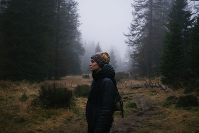 Side view of woman standing in forest