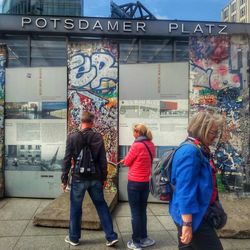 Rear view of people walking on sidewalk in city