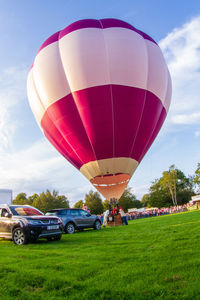 Hot air balloons on field against sky