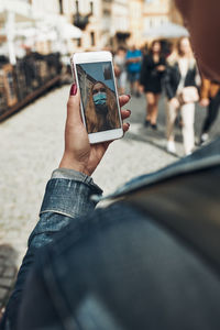 Young woman having video call talking while walking downtown in the evening wearing the face mask