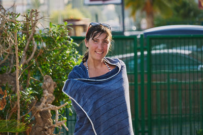 Woman with sunglasses in her hair and towel in a pool looks at camera