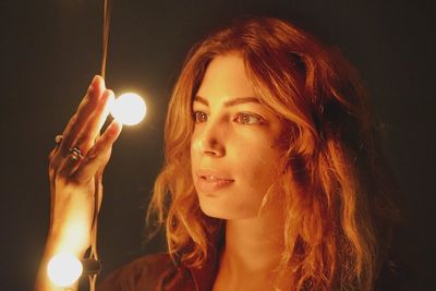 Portrait of young woman holding illuminated lights