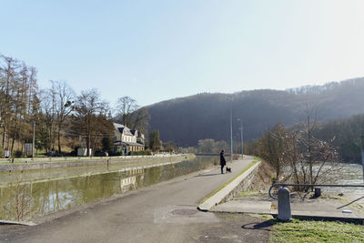 Man walking on road with dog against clear sky